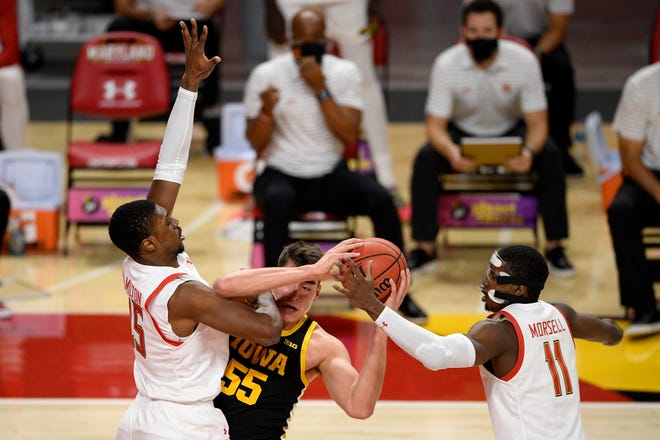 Maryland guard Darryl Morsell (11) and forward Jairus Hamilton, left, battle for the ball with Iowa center Luka Garza (55) during the first half of an NCAA college basketball game Jan. 7 in College Park, Maryland.