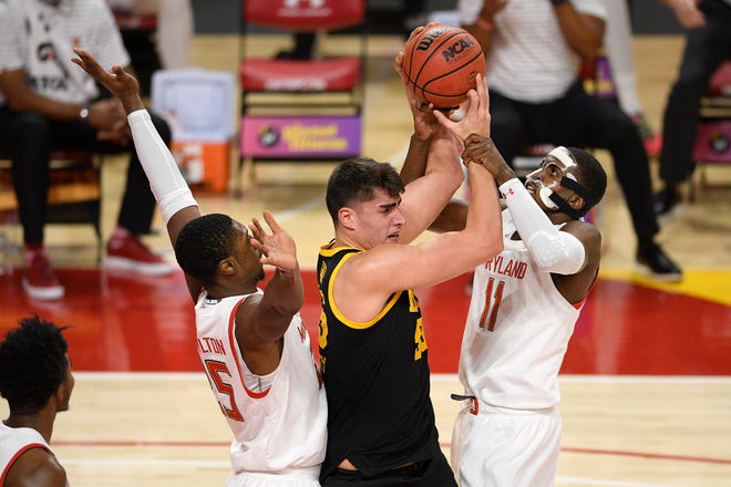 Maryland guard Darryl Morsell (11) and forward Jairus Hamilton, left, battle for the ball with Iowa center Luka Garza, center, during the first half of an NCAA college basketball game Jan. 7 in College Park, Maryland.