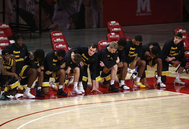 COLLEGE PARK, MARYLAND - JANUARY 07: Members of the Iowa Hawkeyes kneel before tip off against the Maryland Terrapins at Xfinity Center on January 07, 2021 in College Park, Maryland.