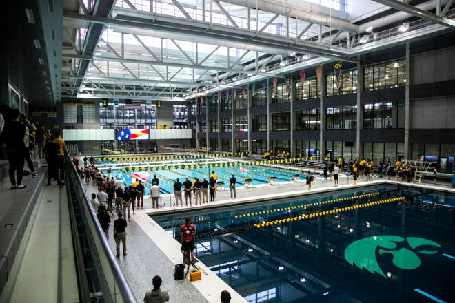 People stand as the national anthem is played before a NCAA Big Ten Conference swimming and diving meet, Saturday, Jan. 16, 2021, at the Campus Recreation and Wellness Center on the University of Iowa campus in Iowa City, Iowa.