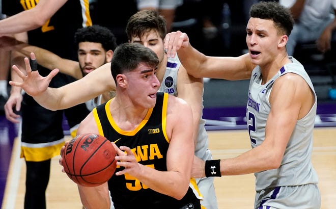 Iowa center Luka Garza (55) looks to pass against Northwestern forward Pete Nance, right, and center Ryan Young during the first half of an NCAA college basketball game in Evanston, Ill., Sunday, Jan. 17, 2021. (AP Photo/Nam Y. Huh)