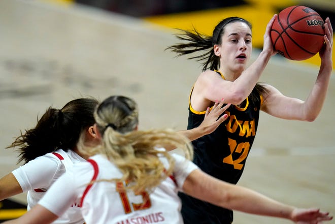 Iowa guard Caitlin Clark, right, looks to pass to a teammate as she is pressured by Maryland guard Katie Benzan, left, and guard Faith Masonius during the first half of an NCAA college basketball game, Tuesday, Feb. 23, 2021, in College Park, Md.