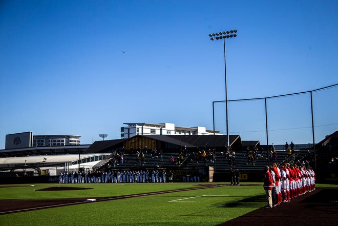 Iowa Hawkeyes and Nebraska Cornhuskers players stand as the national anthem is played before a NCAA Big Ten Conference baseball game, Friday, March 19, 2021, at Duane Banks Field in Iowa City, Iowa.