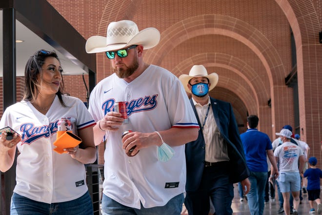 Josh Johnson and Zoe Aguilar walk through the concourse of Globe Life Field before the Texas Rangers' home opener against the Toronto Blue Jays in Arlington, Texas.