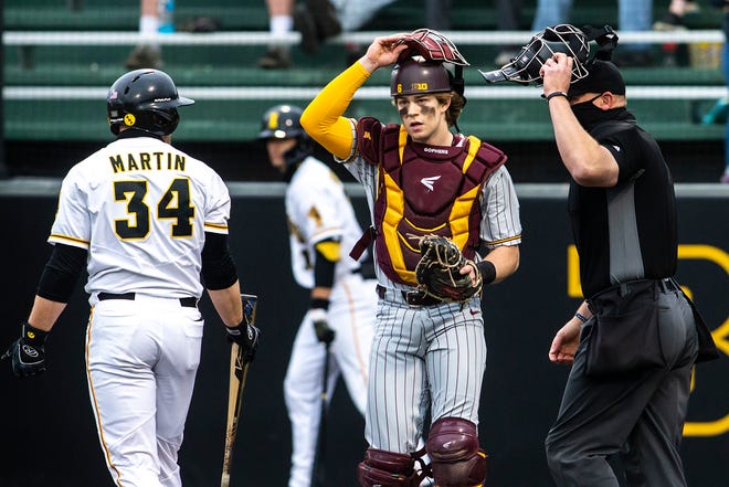 Minnesota catcher Chase Stanke (6) adjusts his face mask as Iowa's Austin Martin (34) reacts to striking out during a NCAA Big Ten Conference baseball game, Friday, April 9, 2021, at Duane Banks Field in Iowa City, Iowa.
