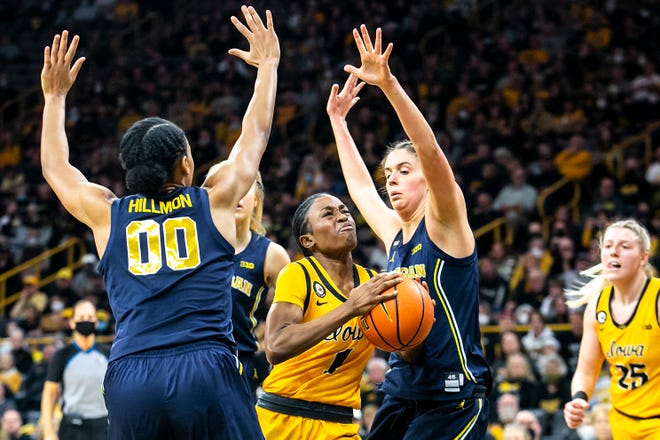 Iowa guard Tomi Taiwo (1) drives to the basket as Michigan forwards Emily Kiser, right, and Naz Hillmon (00) defend during a NCAA Big Ten Conference women's basketball game, Sunday, Feb. 27, 2022, at Carver-Hawkeye Arena in Iowa City, Iowa.