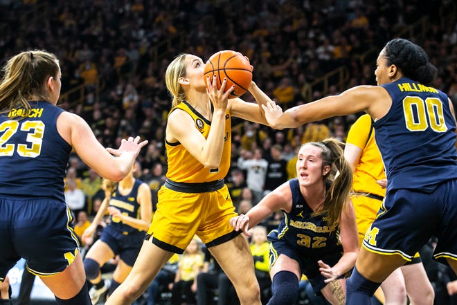 Iowa guard Kylie Feuerbach, center, drives to the basket as Michigan guard Leigha Brown (32) and Michigan forward Naz Hillmon (00) defend during a NCAA Big Ten Conference women's basketball game, Sunday, Feb. 27, 2022, at Carver-Hawkeye Arena in Iowa City, Iowa.