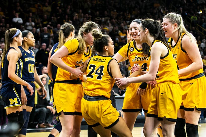 Iowa guard Gabbie Marshall (24) gets helped up by teammates Kate Martin, McKenna Warnock, Caitlin Clark and Monika Czinano during a NCAA Big Ten Conference women's basketball game against Michigan, Sunday, Feb. 27, 2022, at Carver-Hawkeye Arena in Iowa City, Iowa.
