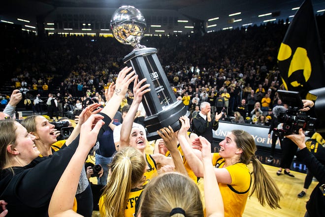 Iowa guards Caitlin Clark and Kate Martin celebrate with their Big Ten regular season championship trophy after a NCAA Big Ten Conference women's basketball game against Michigan, Sunday, Feb. 27, 2022, at Carver-Hawkeye Arena in Iowa City, Iowa.