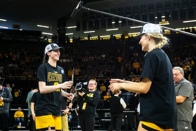 Iowa guard Caitlin Clark, left, hands a pair of scissors to teammate Kylie Feuerbach as they cut down the nets after a NCAA Big Ten Conference women's basketball game against Michigan, Sunday, Feb. 27, 2022, at Carver-Hawkeye Arena in Iowa City, Iowa.