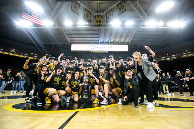 Iowa Hawkeyes players pose for a photo while celebrating with their Big Ten regular season championship trophy with head coach Lisa Bluder, right, after a NCAA Big Ten Conference women's basketball game against Michigan, Sunday, Feb. 27, 2022, at Carver-Hawkeye Arena in Iowa City, Iowa.